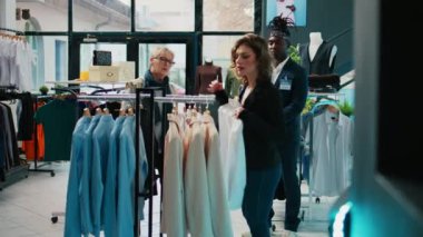 Moda tasarımcısı düzenli müşterilere kıyafet ürünleri öneriyor, mağaza çalışanları yaşlı kadınların indirimli kıyafet almasına yardım ediyor. Alışveriş çılgınlığı sırasında müşterilere yardımcı olan tezgahtarlar. Kamera B.