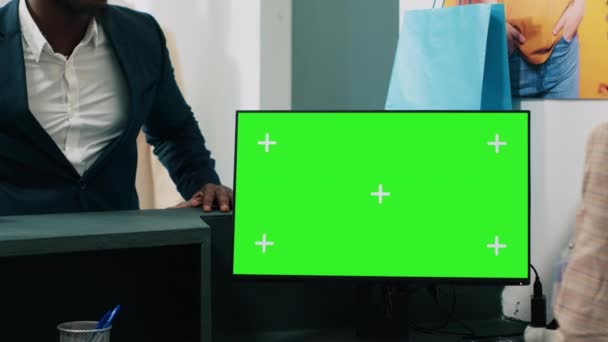 アフリカ系アメリカ人労働者は チェックアウトカウンターで緑色のディスプレイを備えたコンピュータを使用し 顧客のためのバッグに服を置きます 従業員は コピースペースのモックアップ画面を示すPcを見ています カメラ — ストック動画