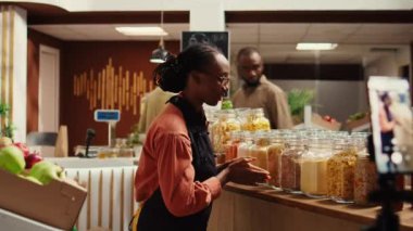 Eko-mağaza çalışanı sosyal medyada yeni yetiştirilmiş ürünleri ve kimyasalları tanıtmak için ticari videolar kaydediyor. Afro-Amerikan film yapımcısı, doğal ürün reklamı. Kamera B.