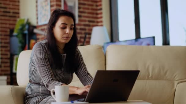 自营职业妇女坐在沙发上 专注于完成个人办公室的任务 致力于在笔记本电脑上输入数据 急于在截止日期前完成项目的自由女商人 — 图库视频影像