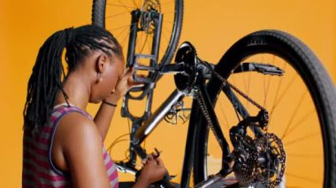 Bisiklet tekerleğini döndürmek için pedalları iten, kontrol eden ve tamir etmek için tornavida ve hex soket anahtarı kullanan bir mühendis. Profesyonel test motoru kolu ve zincir halkaları, kamera B