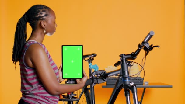 Woman Holds Green Screen Tablet Using Advertise Bike Repair Shop — Stock Video
