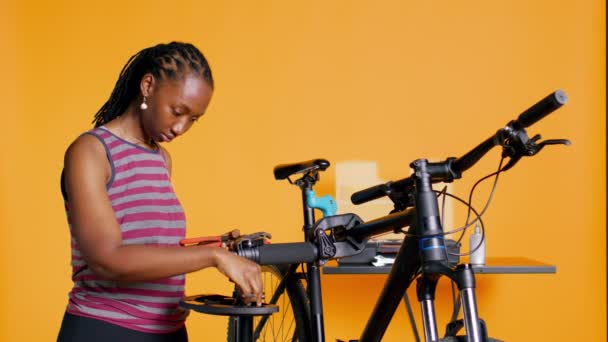 アフリカ系アメリカ人メカニックは 壊れたクライアントの自転車 スタジオの背景を修理する前に作業ツールを準備します 自転車 カメラBの修理を開始する準備ができた機械装置を整理する専門家 — ストック動画
