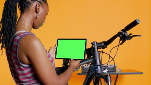 快乐的女人在模仿平板电脑的教学视频之后 学习修理破碎的自行车 在绿色屏幕设备 摄像头B的在线指导下 微笑着骑自行车的业余爱好者们 修理自行车很开心 — 图库视频影像