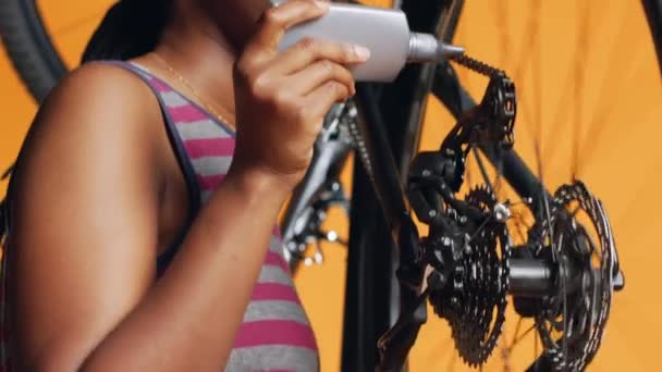不良な自転車チェーン オレンジスタジオの背景を修復するために専門の接着剤を使用した経験豊富なサービスマン 検査プロセス中に自転車部品に接着剤を塗布する労働者 ショットを閉じる — ストック動画