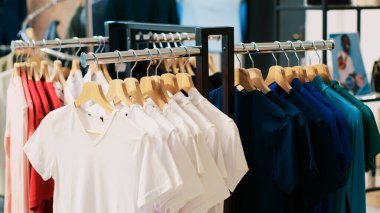 Askı ve askılarla dolu boş modern butik, moda mağazasında asılı şık mallar. İndirimli kıyafet ve aksesuarlar müşterilerin gelip satın almasını bekliyor.