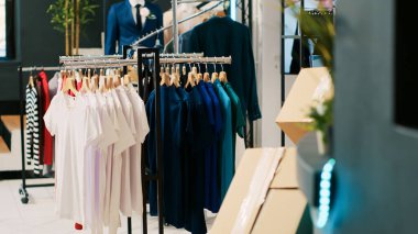 Gündelik ve resmi giysi ürünleri olan boş modern butik, askılarda ve raflarda şık giysileri olan perakende mağazası. Alışveriş merkezinin içindeki giyim mağazası, şık mallar ve aksesuarlar..