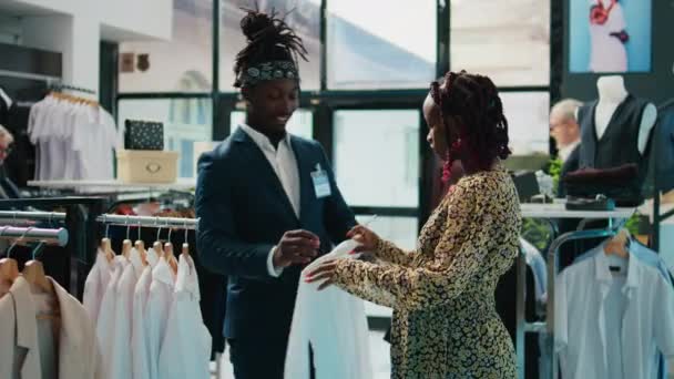 零售助理向顾客展示新的服装系列 推荐百货商店里孕妇的颜色和尺寸 非裔美国人客户向工人寻求帮助 摄像头B — 图库视频影像