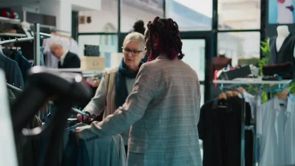 在购物中心的百货商店里 非洲裔美国人零售店员向资深顾客展示新的时装系列 孕妇助手向常客提供色彩建议 消费主义 摄像头B — 图库视频影像
