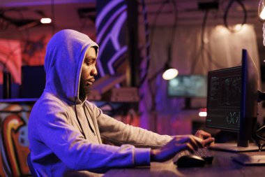 İnternet suçlu hackleme sunucusu, şifre kırma ve bilgi çalma. Başlıklı Afrikalı Amerikalı adam çevrimiçi dolandırıcılık planlıyor ve bilgisayardaki fidye yazılımını karanlık odada kodluyor.