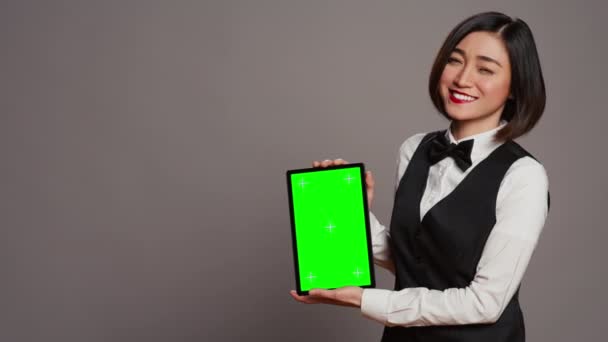 女服务员在平板电脑上展示绿色显示屏 在屏幕上显示铬色模板 带有弓形和带空白复制空间布局的制服保持装置的接待员 摄像头B — 图库视频影像