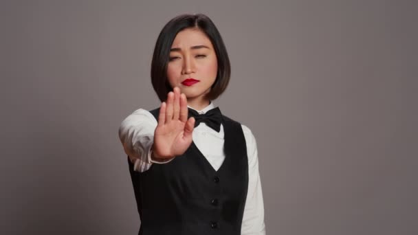 アジアの管理者は スタジオで育ったパームで停止サインを示し 否定的なシンボルを提示し 不承認を表明します 女性のレセプションはジェスチャーを行わず 不満を感じます カメラ — ストック動画