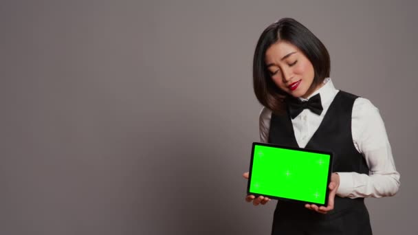 カメラに緑色のタブレットが付いているアジアの受信機は現代ガジェットのモックアップのテンプレートを提示します コピースペースのレイアウトディスプレイ グレースタジオを見るホテルコンシェルジュ カメラ — ストック動画