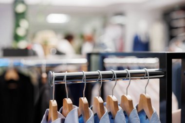 Moda giyim mağazasının metal rafında asılı duran satılık kıyafetler. Erkek giyim koleksiyonundan mavi resmi erkek gömlekleri son gelen askılar, alışveriş merkezindeki müşteriler için sergileniyor