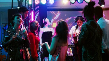 Modern kadın DJ panelini sahnede kullanıyor ve kulüp partisinde canlı elektronik müzik yaratıyor, ses kulüpleri ekipmanları. Kulaklıklı acayip bir kız dans pistindeki insanlara müzik hazırlıyor..