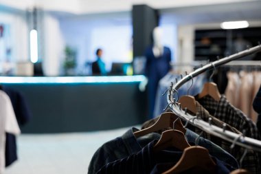 Giysi rafı, arka planda bulanıklık olan boş giyim mağazası mağazasına yakın plan. Alışveriş merkezinin moda butiklerinde hiç kimse olmadan takılan modaya uygun günlük kıyafetler.