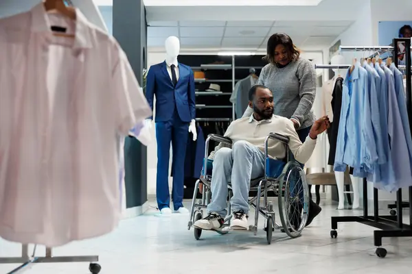 Африканский Американец Инвалидной Коляске Выбирает Одежду Время Шоппинга Подругой Магазине — стоковое фото