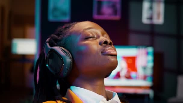 在长时间的研究之后 无忧无虑的学生完成了一个演示 并在音频耳机上放松了音乐 非洲裔美国女孩 带着氛围的曲调很冷 摄像头B — 图库视频影像