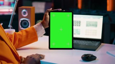 Afrika kökenli Amerikalı kız elinde yeşil ekran düzeniyle tablet tutuyor, finansal ya da ekonomik kurslar için veri analizi yapıyor. Öğrenci cihazda izole edilmiş maket görüntüsü kullanıyor, evden çalışıyor. Kamera A.