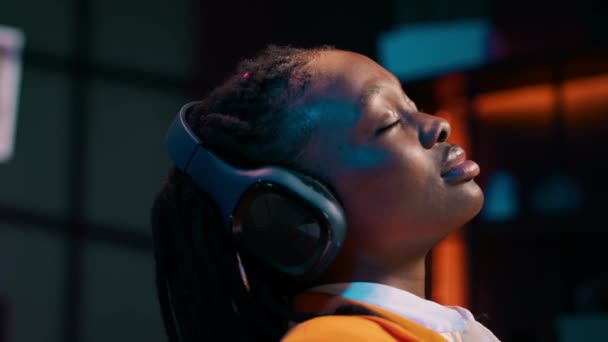 在长时间的研究之后 无忧无虑的学生完成了一个演示 并在音频耳机上放松了音乐 非洲裔美国女孩 带着氛围的曲调很冷 相机A — 图库视频影像