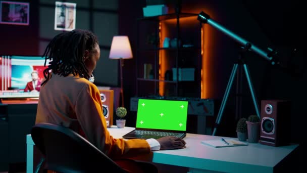 非洲裔美国女青年看着装有绿屏的笔记本电脑 坐在自家办公桌前 准备上大学在线课程 女孩使用Pc与孤立的模型布局 摄像头B — 图库视频影像