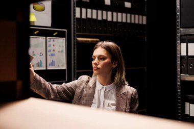 Bürokrasi dosyalarıyla çalışan bir yönetici, muhasebe kayıtlarını analiz ediyor ve yönetim raporunu arıyor. Bookepper arhive odasında mesai yapıyor, depo belgelerini düzenliyor.