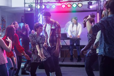 Gece kulübündeki disko partisinde arkadaşlarıyla dans eden tasasız genç bir kadın. Diskotek toplantısında dans pistinde hareketlerini gösteren ve rahatlatan bir kulüp.