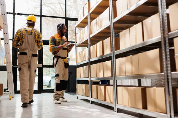 戴耳机的非裔美国人仓库员工监督包裹的安全和维护 邮局发货操作员听音乐 在储藏室工作 — 图库照片