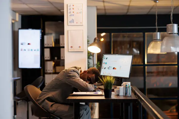 疲れたビジネスマンは 戦略で残業した後 スタートアップオフィスの机のテーブルで寝ています 疲れ切ったアフリカ系アメリカ人のマネージャーで バーンアウト症候群は仕事で休んでいます ビジネスコンセプト — ストック写真
