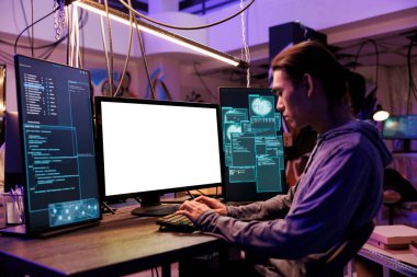 Dolandırıcı, terk edilmiş depoda boş beyaz ekranlı bilgisayar kullanarak hackliyor. Asyalı suçlu kötü niyetli yazılım kodlaması ve boş ekran modeliyle yasadışı faaliyetler yapmak