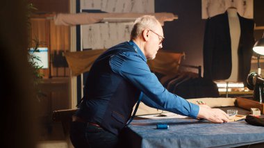 Terzi, küçük iş atölyesinde giysi yapmak için eşyalar seçiyor. Moda tasarımında özel yapım ölçülerle deneyimli bir zanaatkar. Dikiş nakış konsepti.