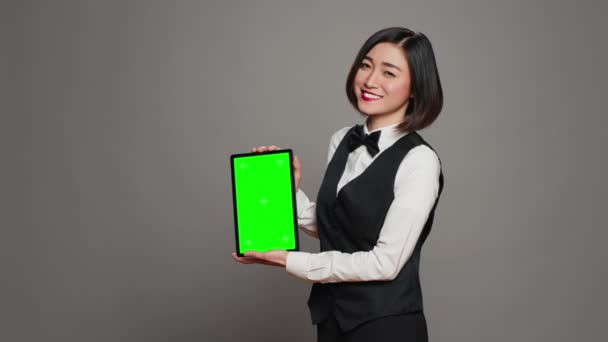 タブレットに緑色のディスプレイを提示する女性コンシェルジュ スクリーン上の染色体テンプレートを示します 空白のコピースペースレイアウトの弓と均一な保持装置を備えたレセプション カメラ — ストック動画