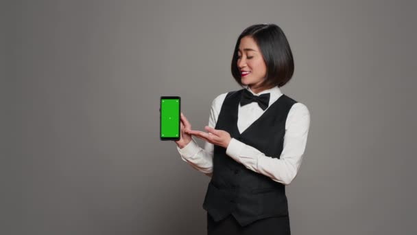 Aziatische Hotel Conciërge Wijzen Naar Telefoon Met Greenscreen Lay Out — Stockvideo