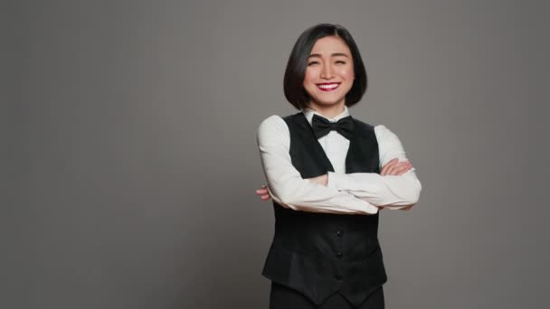 アジアの女性ホテルのコンシェルジュは 受付としてホスピタリティ業界で働く弓でエレガントな制服を着ています レセプション デスク管理者挨拶クライアント 灰色の背景 カメラ — ストック動画