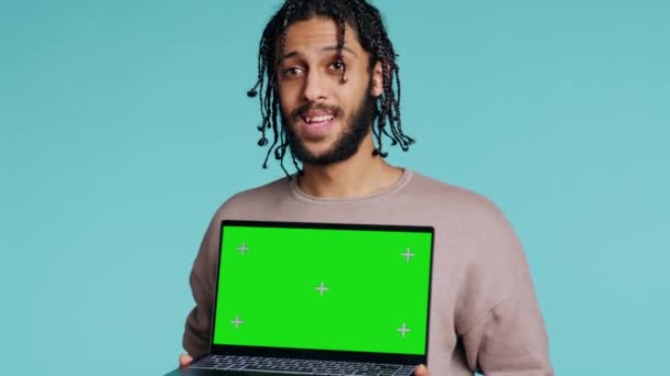 緑色のスクリーン ラップトップを保持しているジョヨウス Bipoc 肯定的な気分 クロマキーノートを提示する笑顔の人 推奨事項を行う スタジオの背景に隔離 カメラB — ストック動画