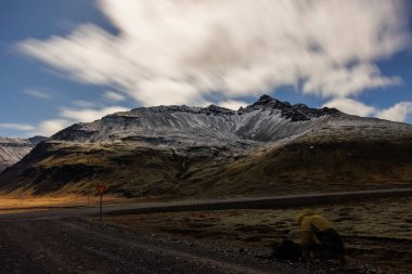 Vadi boyunca dramatik karlı dağlar, gece fotoğrafçılığı kavramı. İzlanda kırsal kesimlerinde, yol manzarasında, karla kaplı tepelerin ve donmuş dağlık arazilerin nefes kesici manzarası..