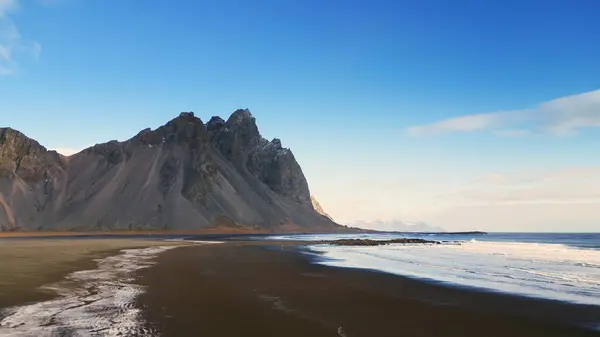海岸沿いのストックスネスビーチ 黒砂のビーチとアイスランド半島のベストラホーン山脈のドローンショット パノラマビューで美しい北欧の風景です スローモーション — ストック写真