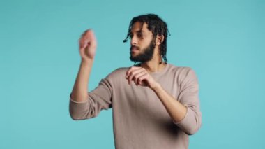 Ortadoğu orkestra şefi hayali notaları takip ederek klasik müzik konseri veriyor. Narin el hareketleri yapan adam, orkestra yönetiyormuş gibi yapıyor, stüdyo arka planı, kamera A