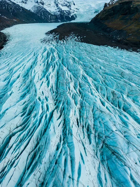 Aerial view of glacier ice cap on wintry region, massive blocks of cracked ice with crevasses in iceland. Spectacular blue diamond shaped rocks creates nordic landscapes, covered frost icebergs.