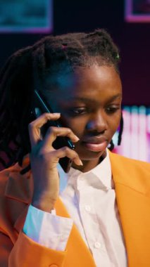 Dikey Video Afrikalı Amerikalı öğrenci cep telefonu hattından çağrıya cevap veriyor, öğretmeniyle ders materyalleri ve bekarlık kağıdında kullanmak üzere ders notları hakkında konuşuyor. Akıl hocasıyla fikir alışverişi yapan bir kız.