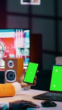 Dikey Video Afrikalı Amerikalı kız ekranda aynı izole model şablonu kullanan modern cihazlara bakarak yeşil ekranlı akıllı telefon ve bilgisayar kullanıyor. Genç kadın telif alanı ekranlarını kontrol ediyor