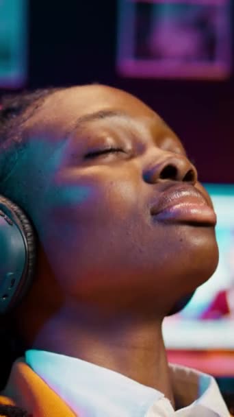 在长时间的研究之后 垂直视频无忧无虑的学生完成了一个演示 并在音频耳机上放松了音乐 带着情调的非洲裔美国女孩 — 图库视频影像