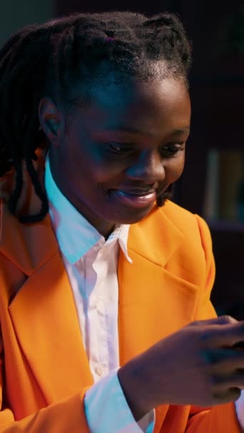 垂直ビデオ アフリカ系アメリカ人の少女がスマートフォンにメッセージを送り 彼女の学士号の最終論文に取り組むのを休む ソーシャルメディア リモートコースで友達とチャットする大学生 — ストック動画