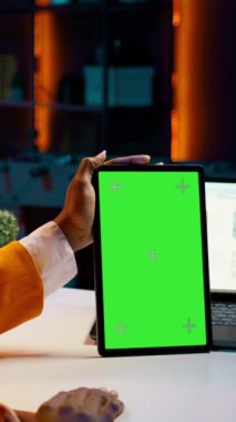 Dikey Afrikalı Afrikalı Amerikalı kız elinde yeşil ekran düzeniyle tablet tutarak finansal ya da ekonomik kurslar için veri analizi yapıyor. Öğrenci aygıt üzerinde izole edilmiş maket görüntüsü kullanır, evden çalışma