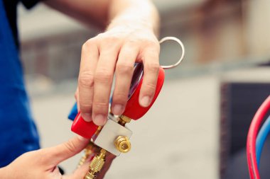 Becerikli tamirci işe başlamadan önce yıllık kondansatör bakımını yapıyor, manifold metre montajı yapıyor. Havalandırma sistemindeki sıvı ve gazların basıncını okuyabilen yetenekli mühendis, kapat.