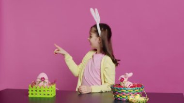 Masada otururken kameranın önündeki tüm yönleri gösteren, yukarı, aşağı, sola ve sağa bakan sevimli küçük çocuk. Etrafa bakan tavşan kulaklı, gülümseyen güzel kız. Kamera A.