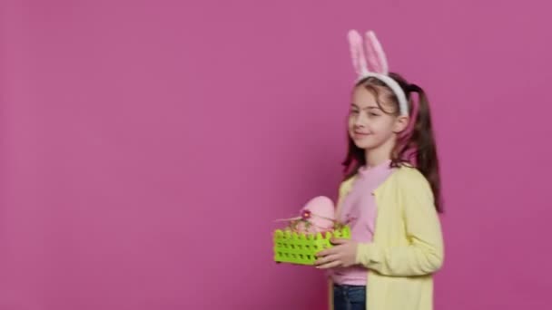 笑容满面的女孩献上她手工制作的装有彩绘鸡蛋和其他节日装饰品的复活节篮子来庆祝节日 快乐的小女孩为她的安排感到自豪 相机A — 图库视频影像