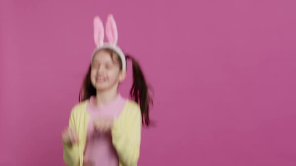 Радостная Беззаботная Школьница Прыгает Студии Имитирует Кролика Прыгает Розовом Фоне — стоковое видео