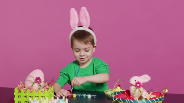 Uśmiechnięty Wesoły Przedszkolak Malujący Jajka Ozdoby Świątecznych Przygotowań Wielkanocnych Wykorzystujący — Wideo stockowe