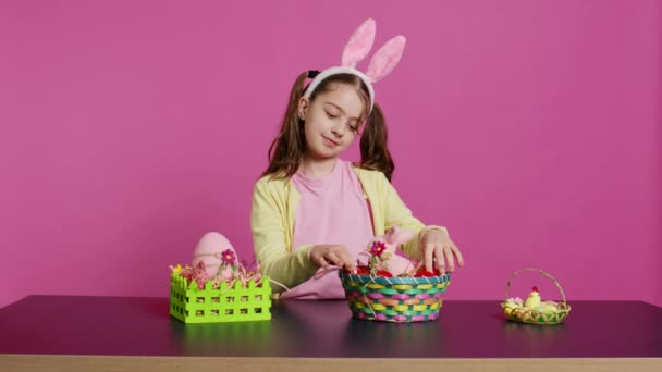 兴奋的小女孩把彩绘的鸡蛋放在篮子里 准备庆祝复活节 做出节日的安排 活泼快乐的学步儿童 长着小兔子耳朵 有创造性的活动 摄像头B — 图库视频影像